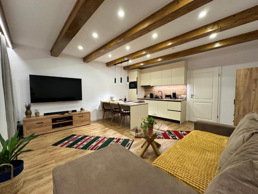 a living room with a couch and a tv and a kitchen at Central House - Modern Apartment in Zărneşti