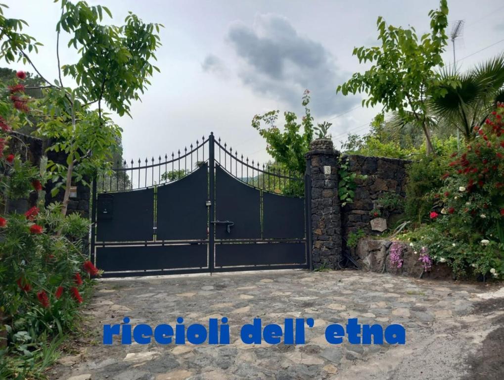 a black gate with a stone wall at Riccioli dell' Etna in Piedimonte Etneo