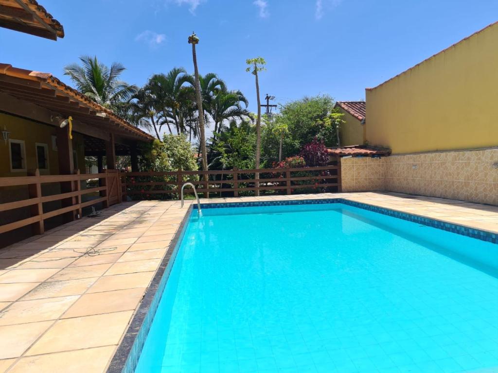a swimming pool with blue water in front of a house at Casa em Praia Seca - Ideal para familia- Piscina- Churrasco- Em Condominio in Araruama