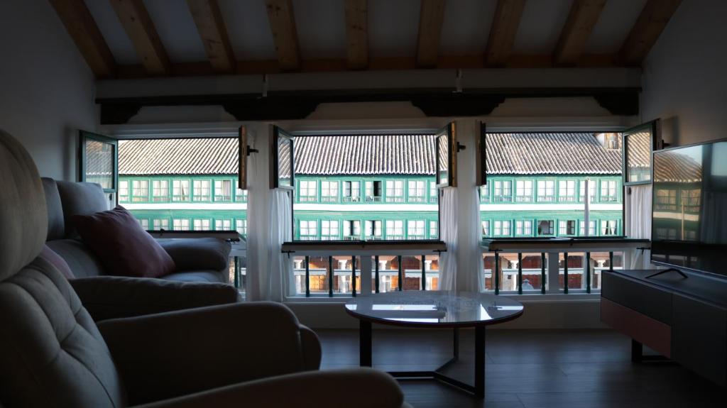 a living room with a couch and a table and windows at Almagro Plaza Apartamento in Almagro
