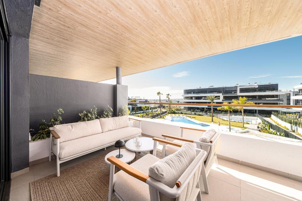 a balcony with a couch and chairs and a table at CasaBlanka Premium Apartment with Pool & Wellness in Torrevieja
