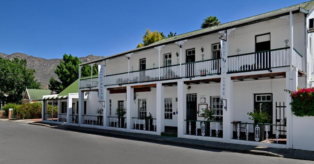 a white building with balconies on a street at Mimosa Lodge in Montagu