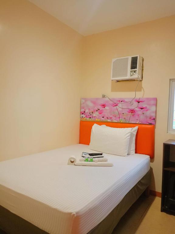a bedroom with a bed with an orange headboard at Rafael Suites Inn in Mojon