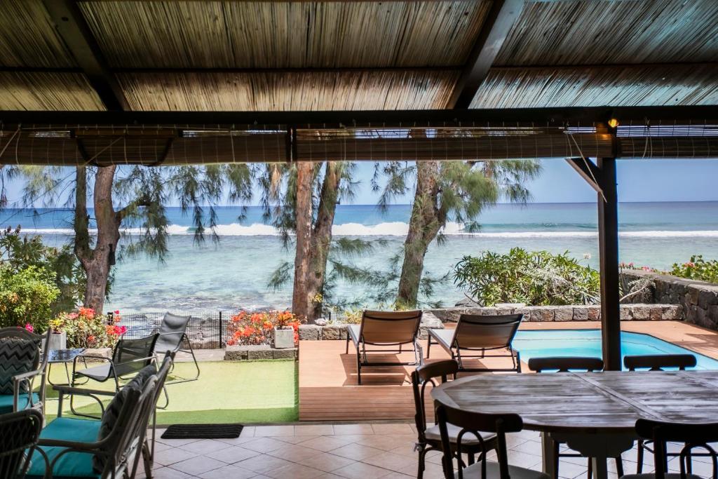 a patio with tables and chairs and a view of the ocean at Beach, Blue Sea, Sunset and Private Pool in Rivière Noire