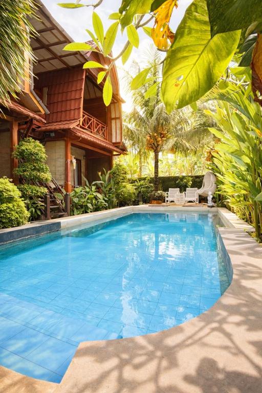a large blue swimming pool in front of a house at Putra Bali Villa by Antara in Klungkung