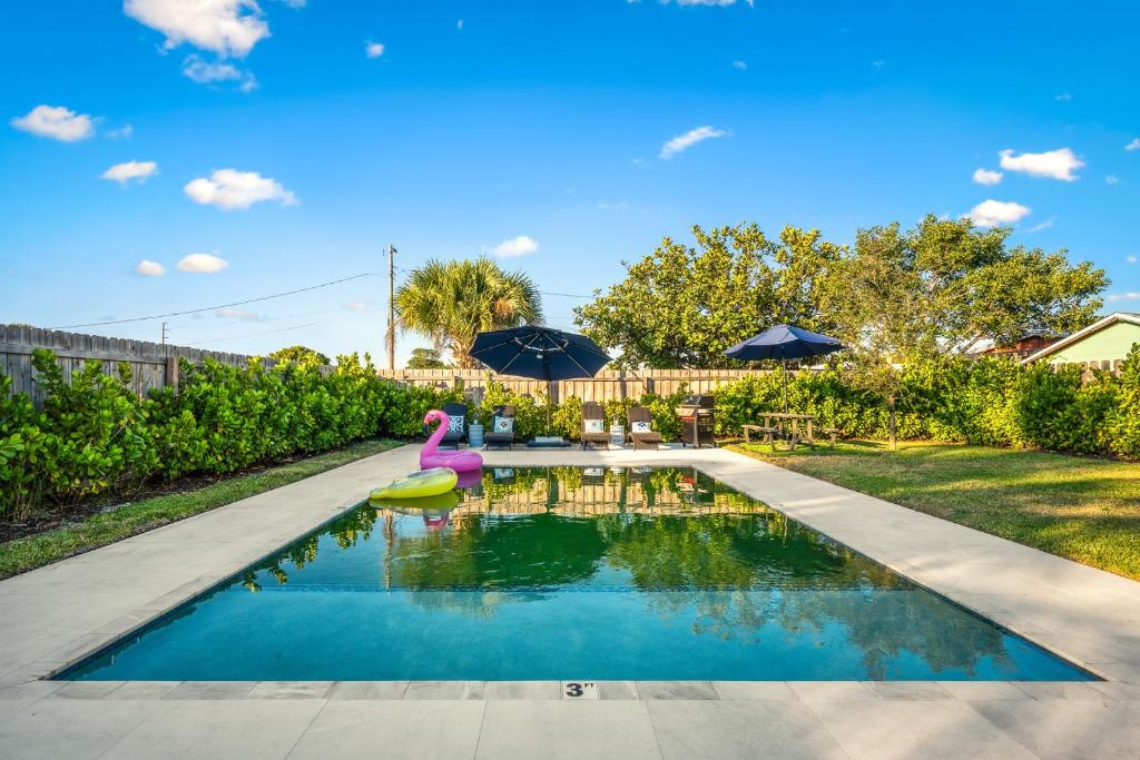 a swimming pool in a yard with an umbrella and a backyard at Delray Oasis - Private Pool - Fenced Yard - Parking - Laundry - Full Kitchen - Convenient Location in Delray Beach