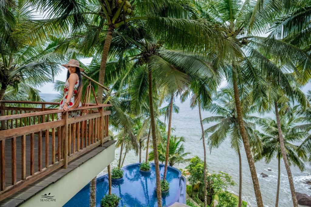 a woman standing on a balcony looking at the ocean at Seascape Beach Retreat in Kannur