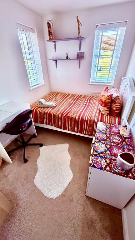 a bedroom with a bed and a desk and windows at Private room in BS14 in Bristol