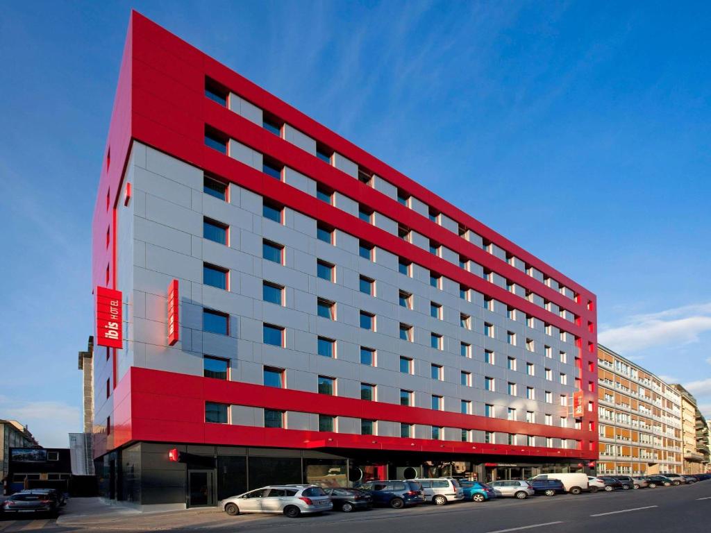 a red building with cars parked in a parking lot at ibis Genève Centre Nations in Geneva