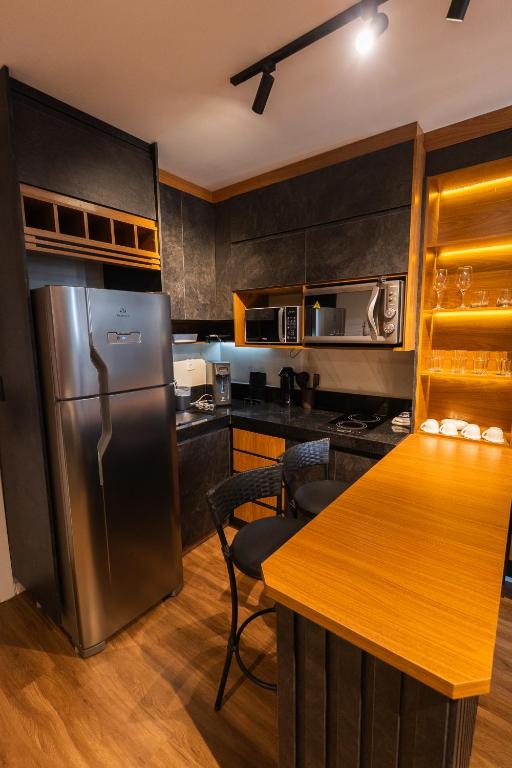 a kitchen with a stainless steel refrigerator and a table at Flat Exclusivo Studio Cuiabá 1604 in Cuiabá