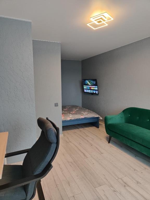 a living room with a green couch and a bed at Satiksmes apartment in Jelgava