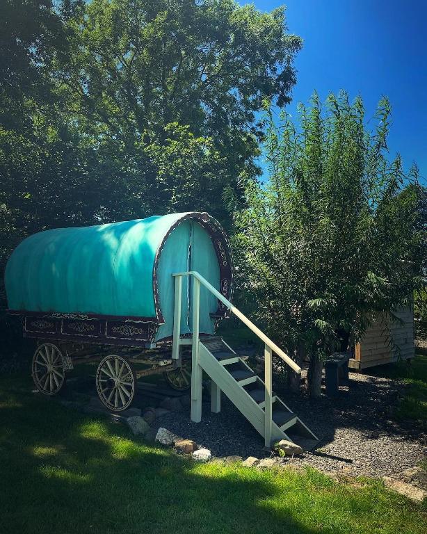 a large blue tank on a wagon with a house at Gypsy bow top caravan in Llangrannog