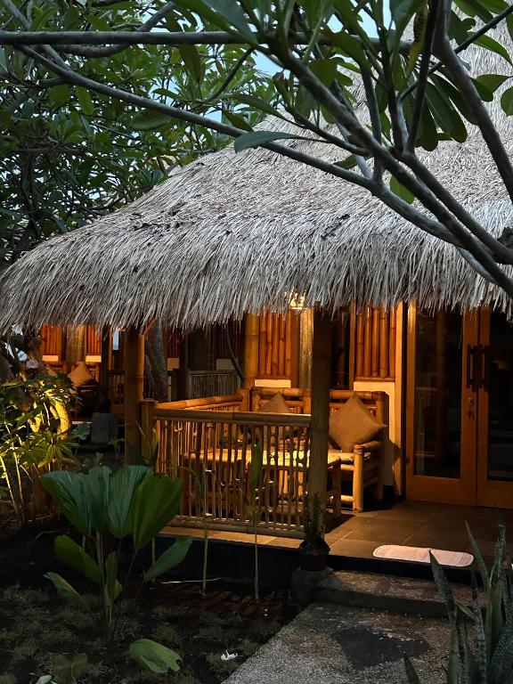 a house with a thatched roof and a porch at Bambuu in Gili Islands