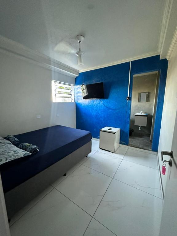 a blue room with a bed and a bathroom at Pousada Amizade in Água Boa