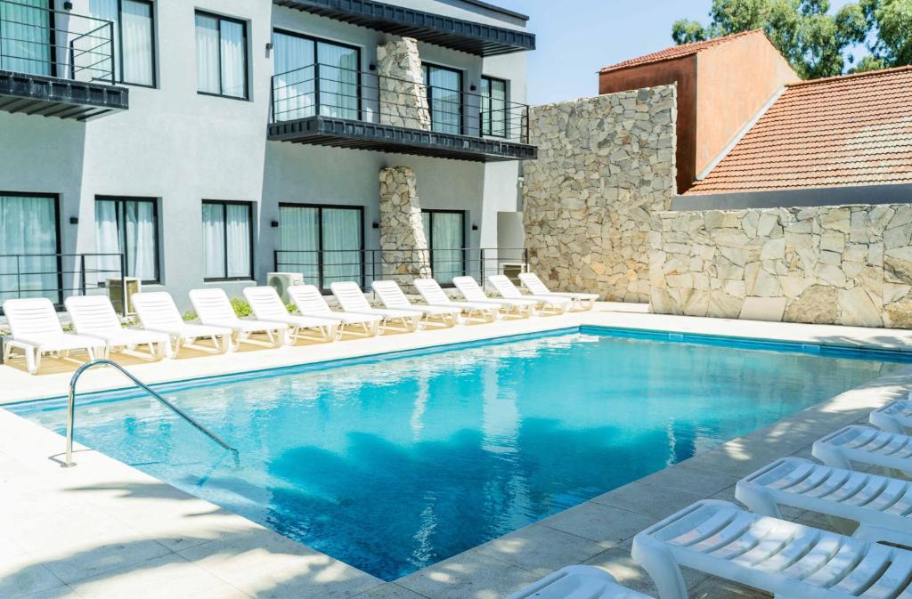a swimming pool with chairs and a building at Palmas de la Laguna by Posada Suiza in San Miguel del Monte