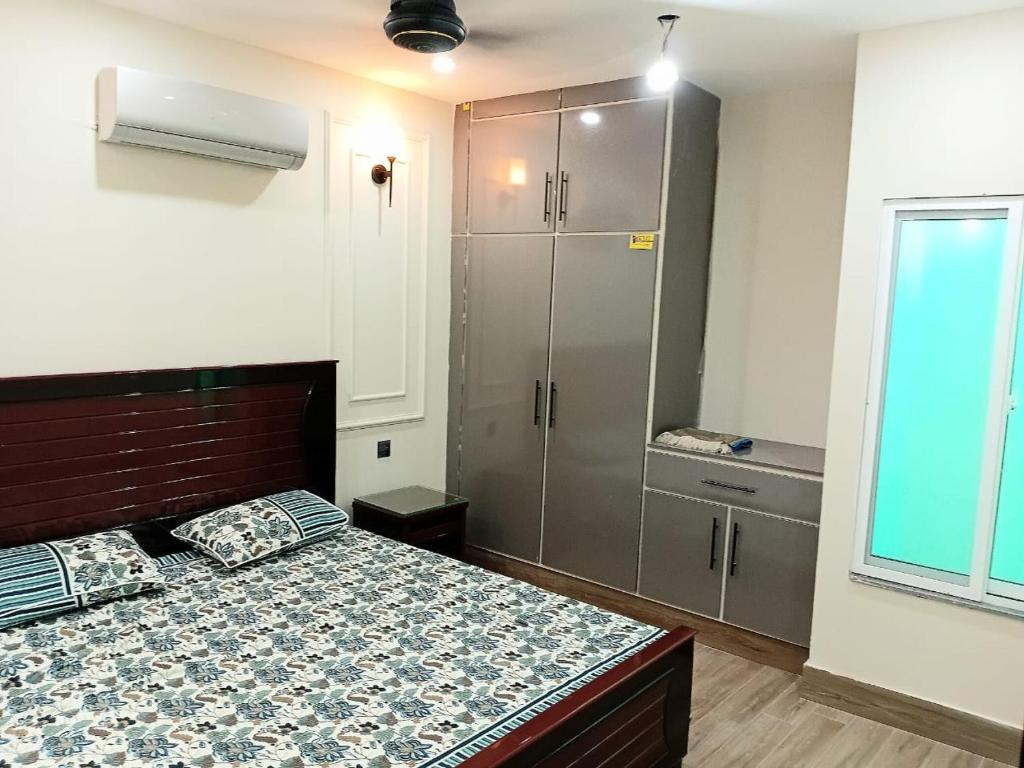 a bedroom with a bed and a cabinet and a window at Alfazal apartment in Lahore