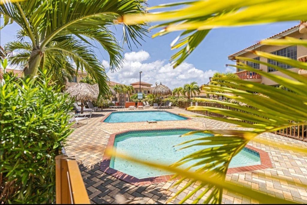 a swimming pool with palm trees and a building at Palma Divine Condo-2BR-2BTH-Pool in Noord