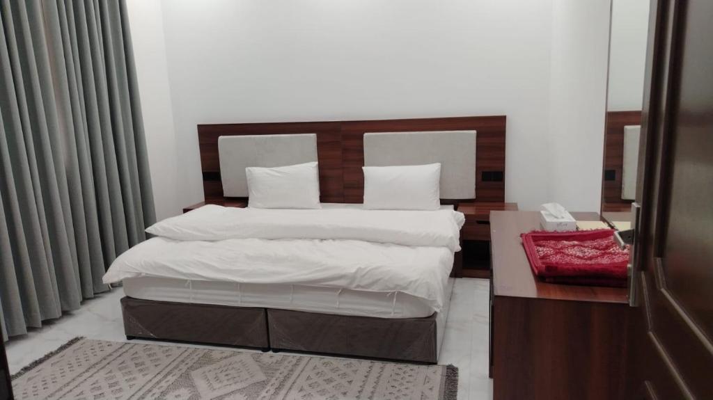 a bed with white sheets and pillows in a bedroom at ﻣﺆﺳﺴﺔ ﺷﻘﻖ ﺍﻟﻘﺎﺭﺍﺕ ﺍﻟﺴﺒﻊ ﺍﻟﻤﺨﺪﻭﻣﺔ in Al Nairyah