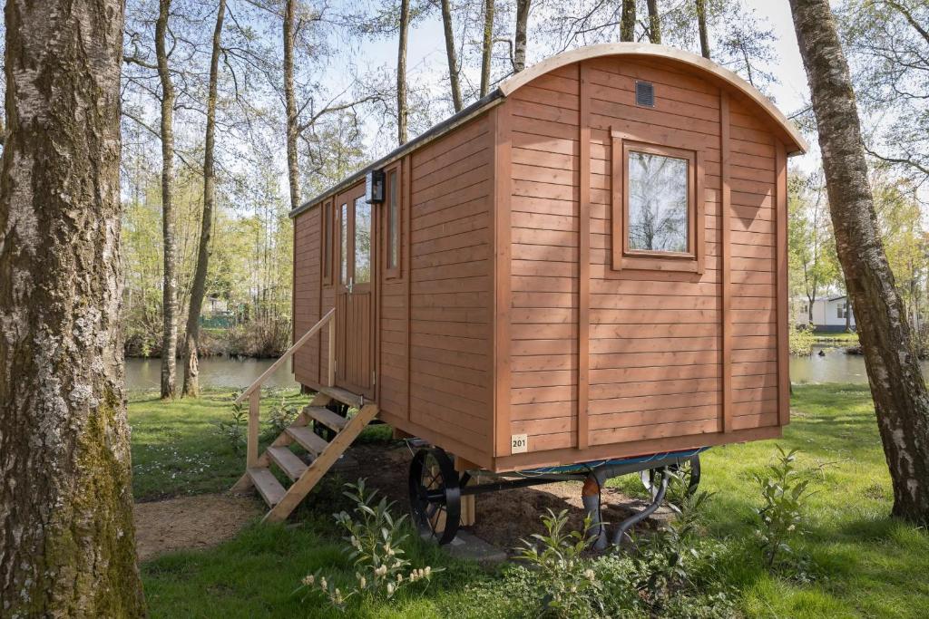 a wooden tiny house sitting in the woods at Camping Papillon Kinrooi - Pipowagen 2p in Kinrooi