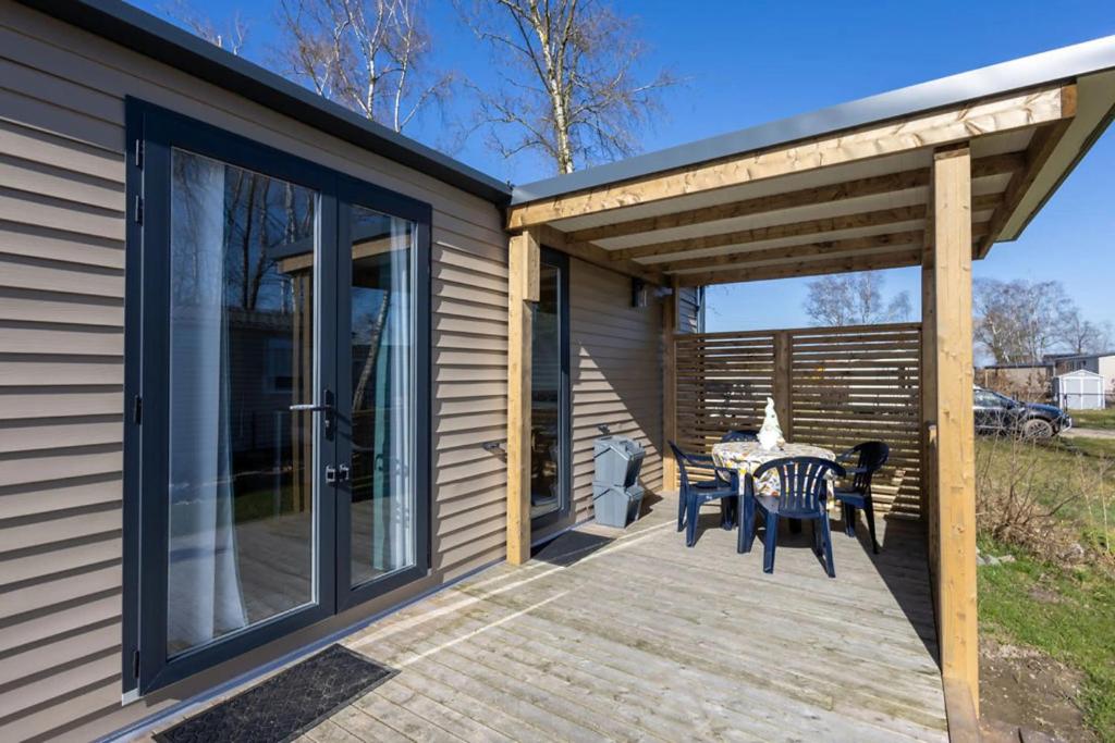 a patio with a table and chairs on a deck at Camping Papillon Kinrooi - Vakantiehuis Familie 6P in Kinrooi