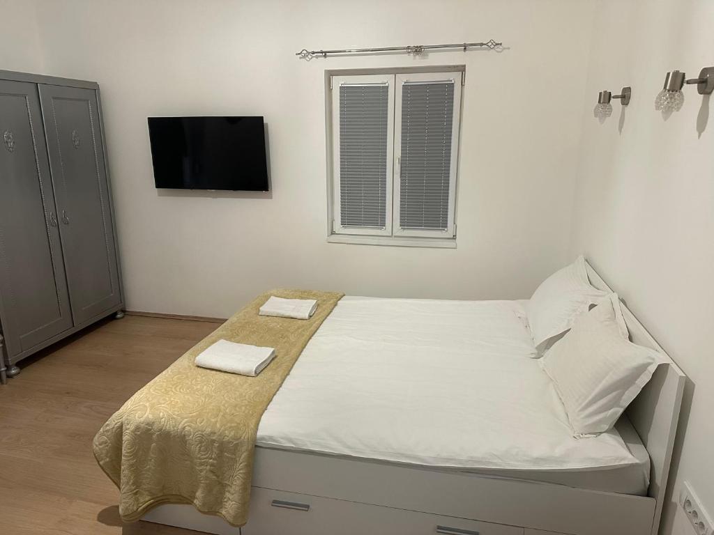 a bedroom with a bed with white sheets and a tv at Natalie's Lodge in Belgrade