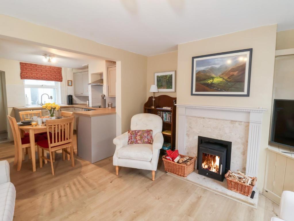 a living room with a fireplace and a kitchen at Lilly Cottage in Woodbridge