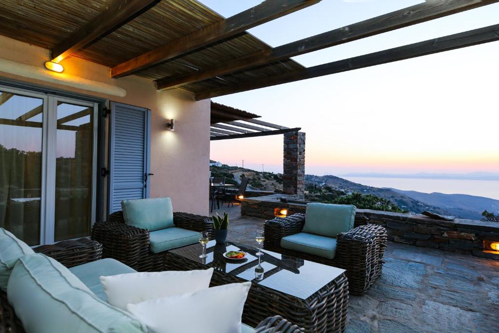 a living room with couches and chairs on a patio at Cycladic Villa with sea view! in Ioulis