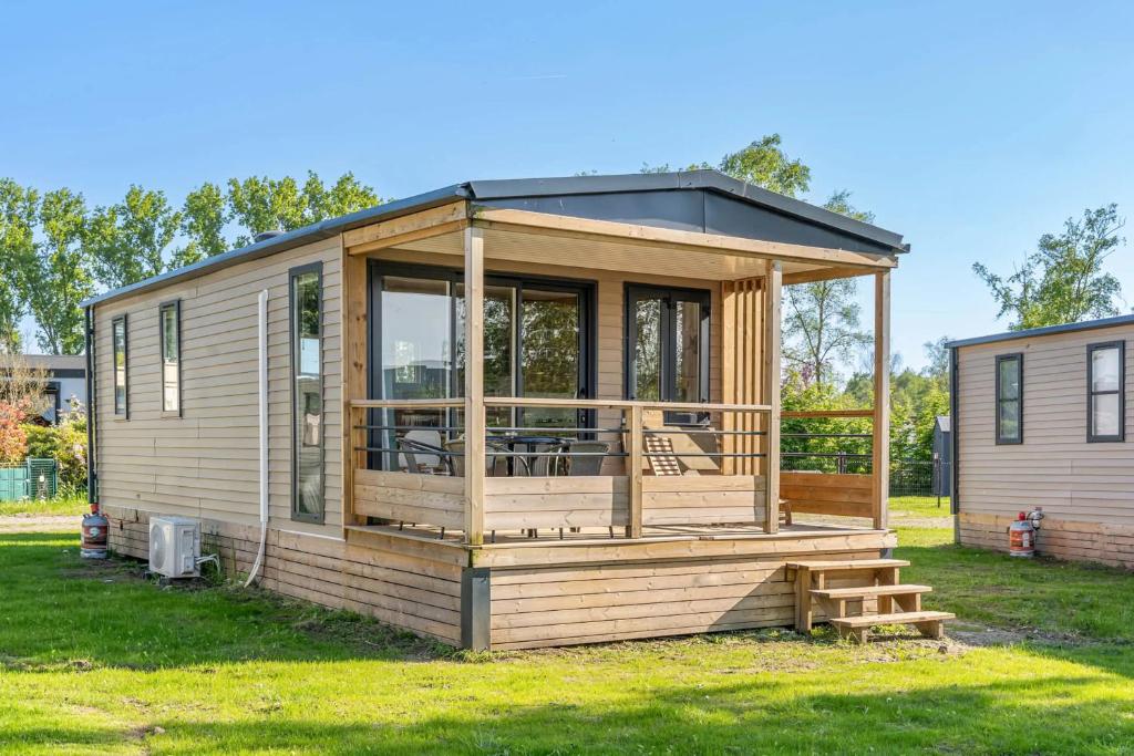 a tiny house with a large deck on the grass at Camping Papillon Kinrooi - Vakantiehuis Premium 4P in Kinrooi