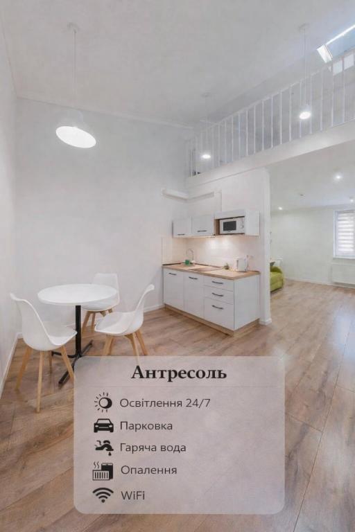 a white kitchen with a table and a sign in a room at Antresol in Lviv