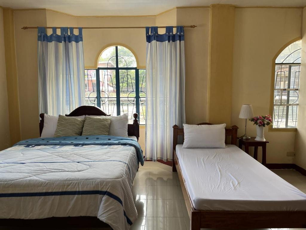 a bedroom with two beds and a window at Brussels Garden Inn in Lagawe