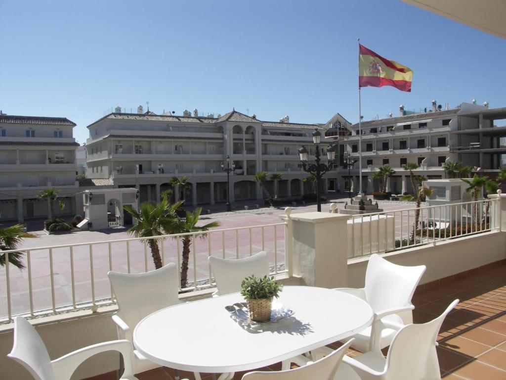 a balcony with a white table and white chairs at Plaza España - Central 3 Bedroom apartment - LUAL in Nerja