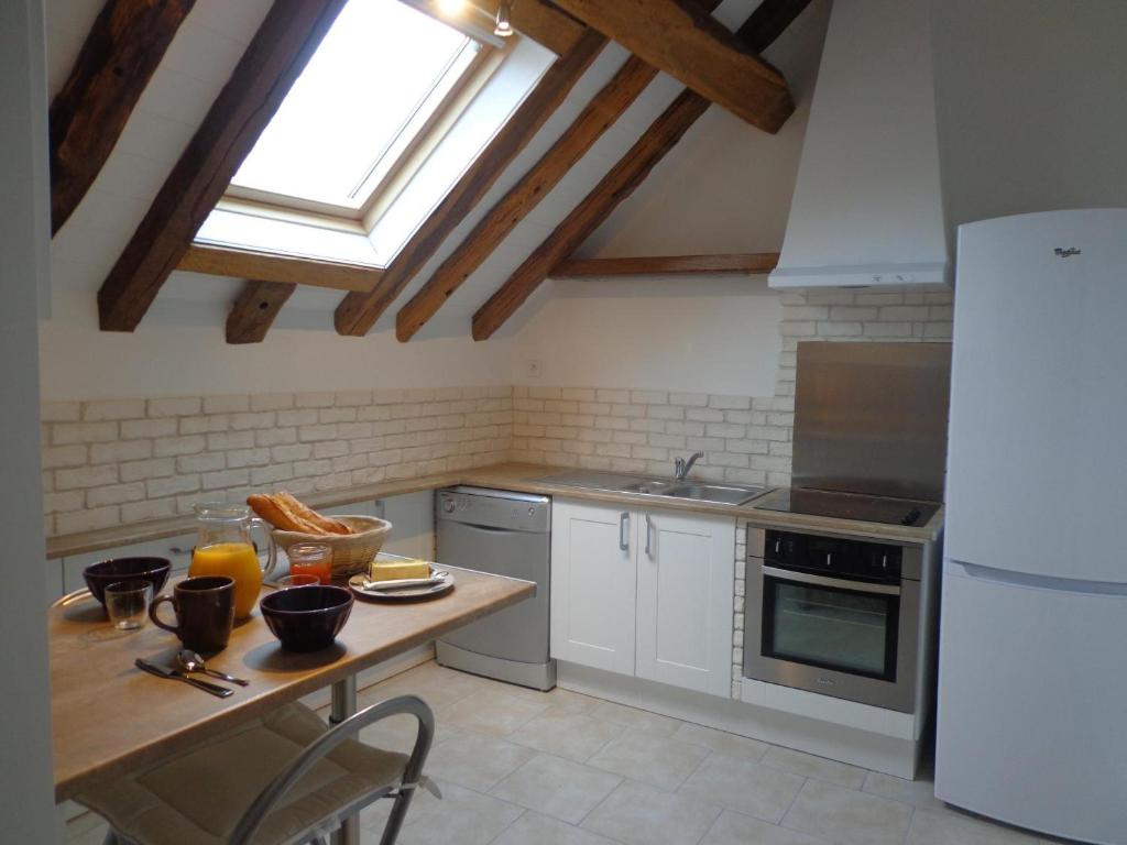 a kitchen with a table and a white refrigerator at Gîte De La Petite Croix Blanche in Les Riceys