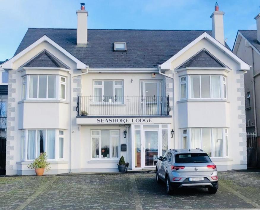 a car parked in front of a white house at Seashore Lodge Guesthouse in Galway