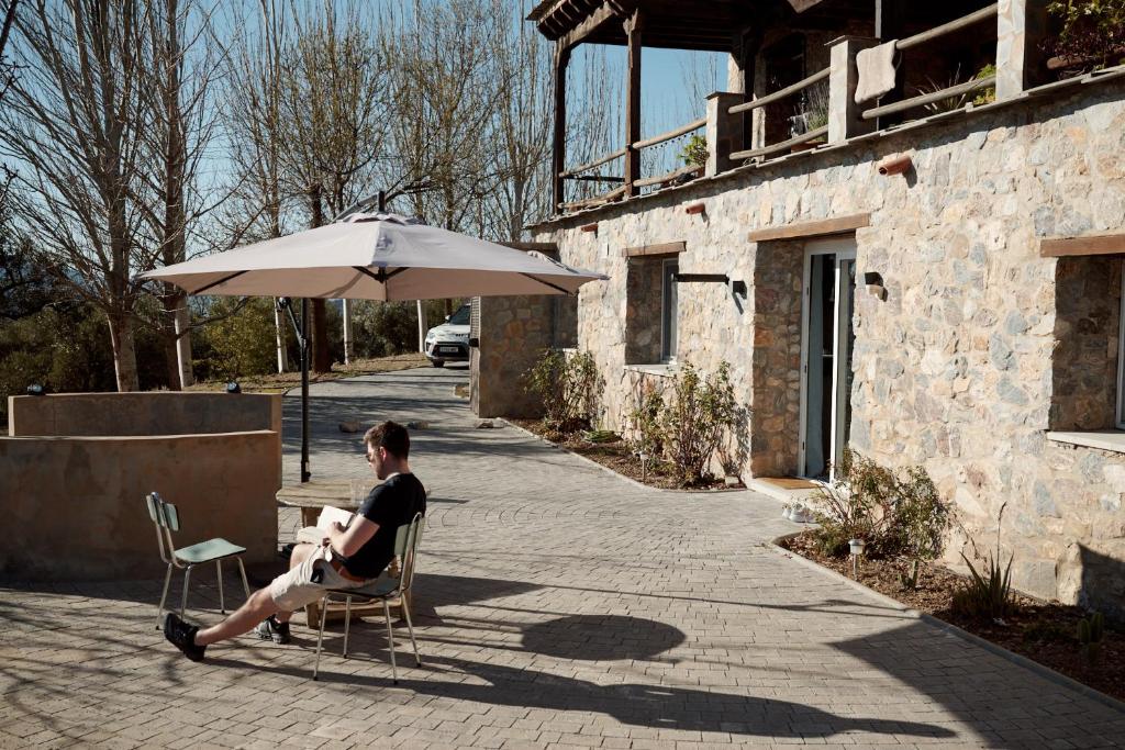 a man sitting in a chair under an umbrella at Casa del Bienestar in Lanjarón