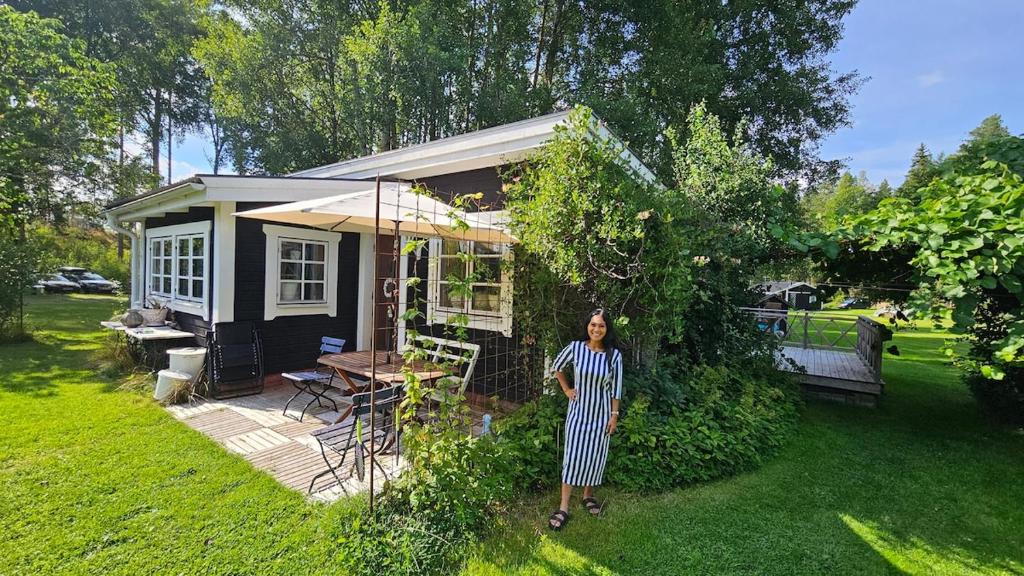 a woman standing in front of a tiny house at Björklunda, lakes, canoe, sauna in Näfstorp