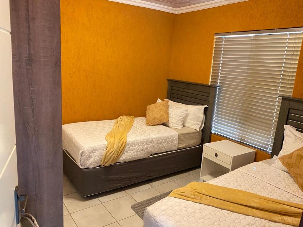 two beds in a room with orange walls at 26 Rubens apartments in Secunda