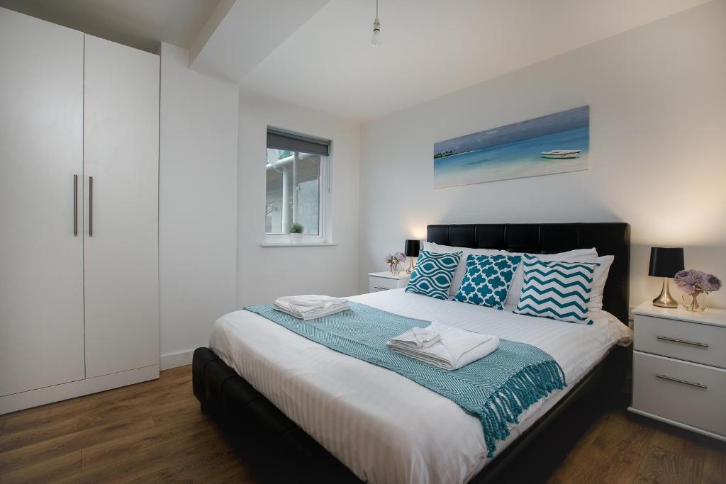 a bedroom with a large bed with blue and white pillows at Charming 1Bed Flat with Private Balcony, Super Double Bed, Free Allocated Parking, and Easy Access to Tube & Central London in Enfield