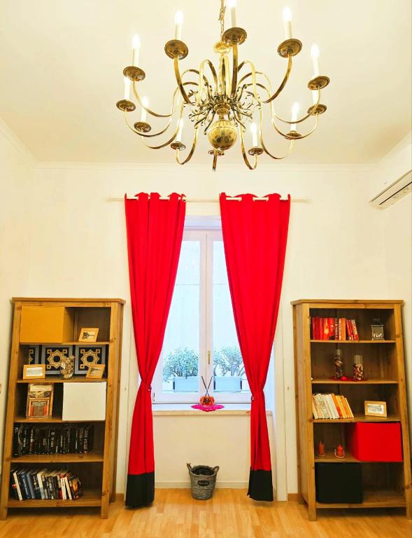 a chandelier and red curtains in a room with a window at Agora Apartments -Friend's House Sorrento in Sorrento