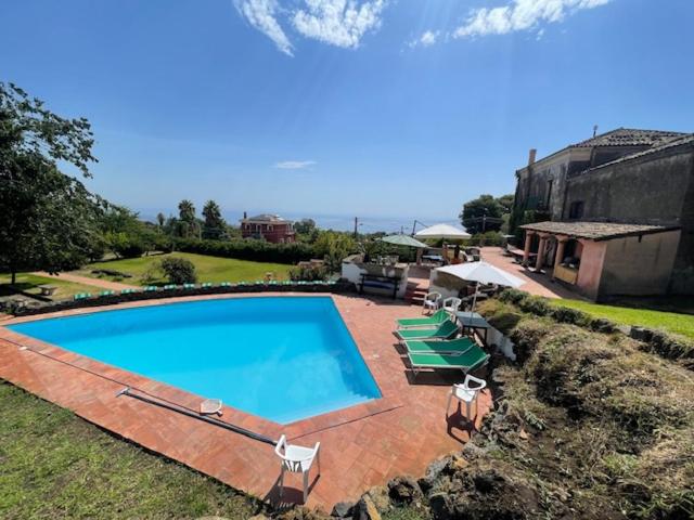 a large swimming pool with chairs and a house at Independent accommodation on Etna in San Giovanni Montebello