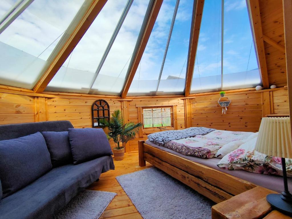 a bedroom with a bed and a couch in a room with windows at Magic Kota - Sternenguckerhaus in Wilhelminenthal