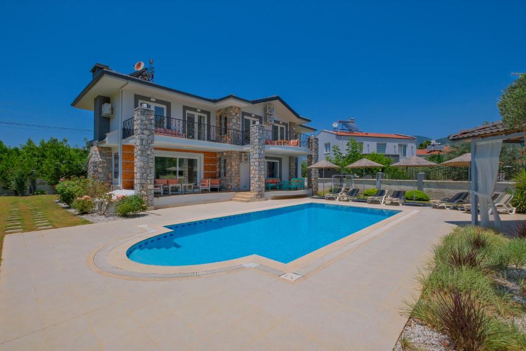 ein Haus mit einem Swimmingpool davor in der Unterkunft Villa Brezza in Fethiye