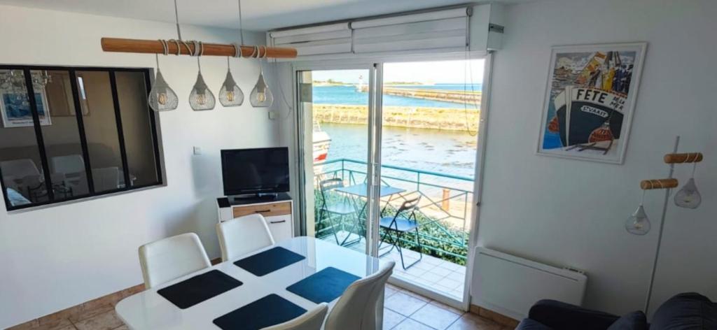 a living room with a table and a view of the ocean at Appartement T2 face à la mer in Saint-Vaast-la-Hougue