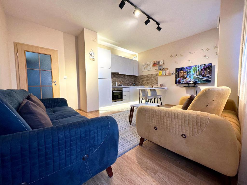 a living room with a blue couch and a kitchen at Aria Apartment in Prishtinë