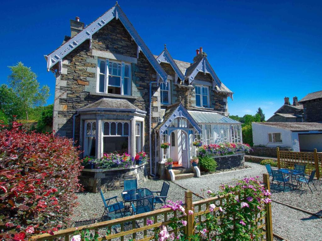 an old stone house with a conservatory and flowers at Elim Bank Guest House in Windermere