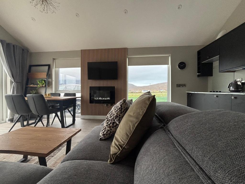 a living room with a gray couch and a table at Beyond The Waters Edge Chalet in Dooagh