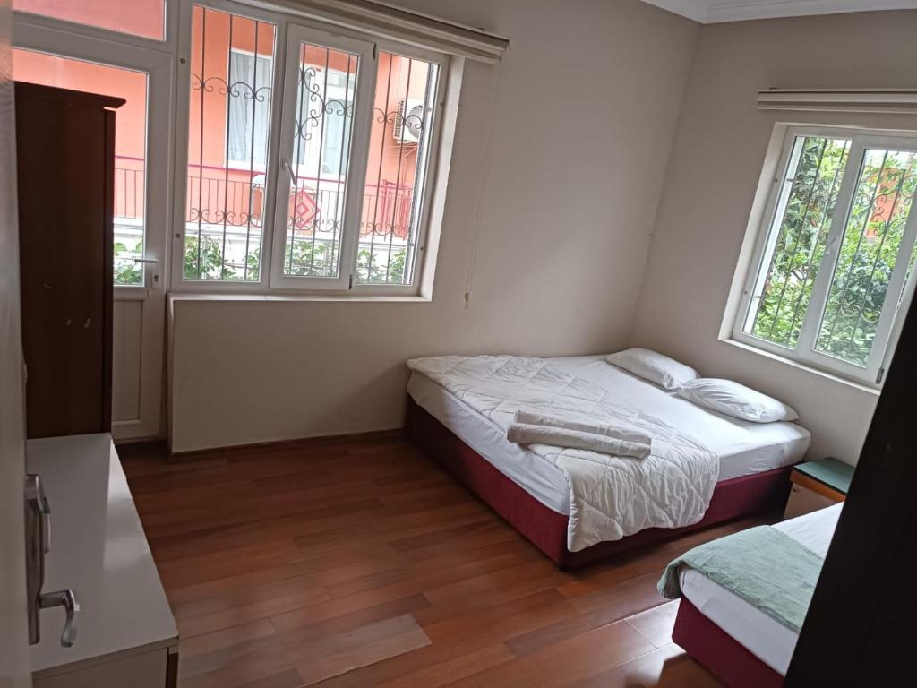 a small bedroom with a bed and two windows at Dilara Hotel Pansiyon in Antalya