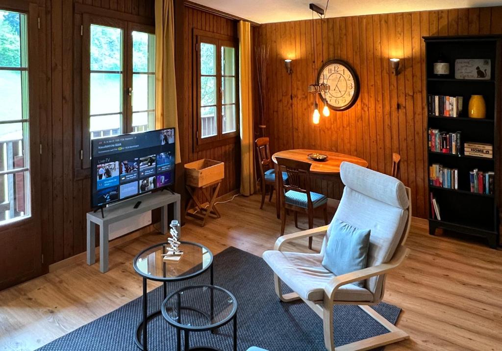a living room with a tv and a chair and a table at Chalet Oasis - Your Alpine Hideaway in Bürglen