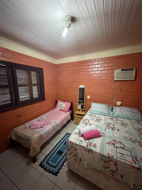 a bedroom with two beds and a tv in it at Casa praia bella torres in Passo De Torres