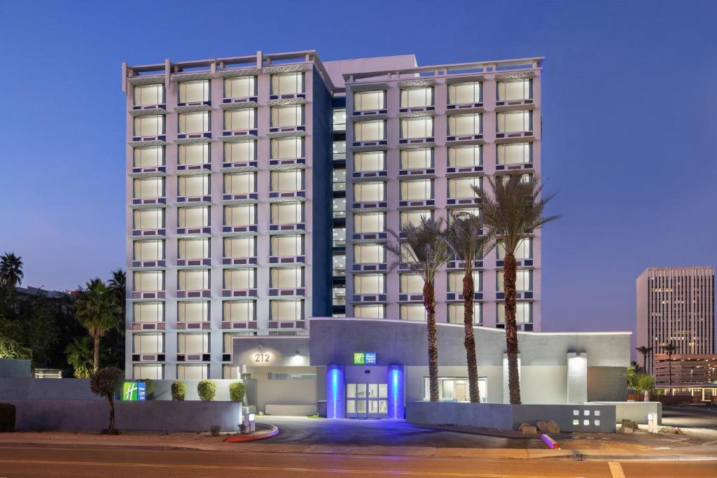 a hotel with palm trees in front of a building at Holiday Inn Express & Suites Phoenix - Midtown, an IHG Hotel in Phoenix