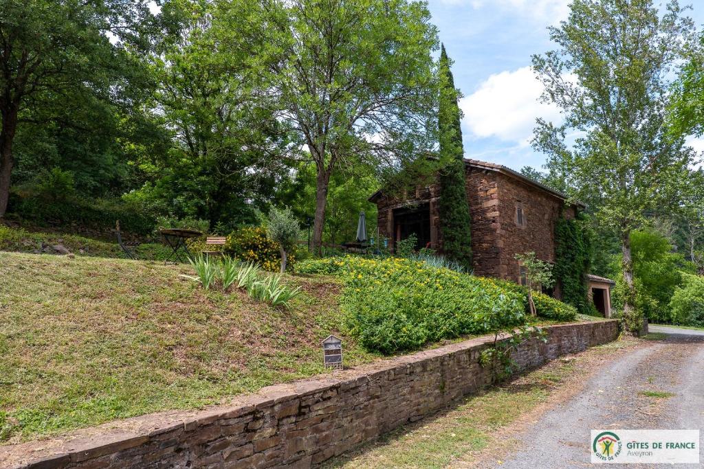 a stone retaining wall next to a brick house at Le Gîte de Saint Izaire in Saint-Izaire